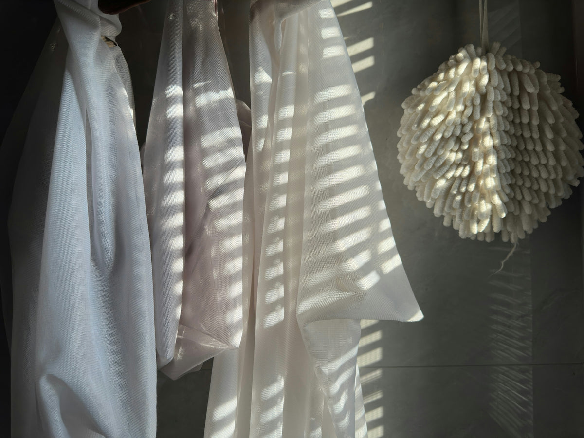 White linen shirts hanging in warm striped sunlight